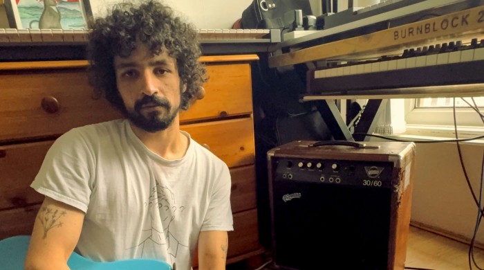 Man playing guitar next to keyboard 